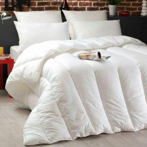 White quilted 13.5 tog duvet with soft-touch cotton cover styled on a bed against an exposed brick wall