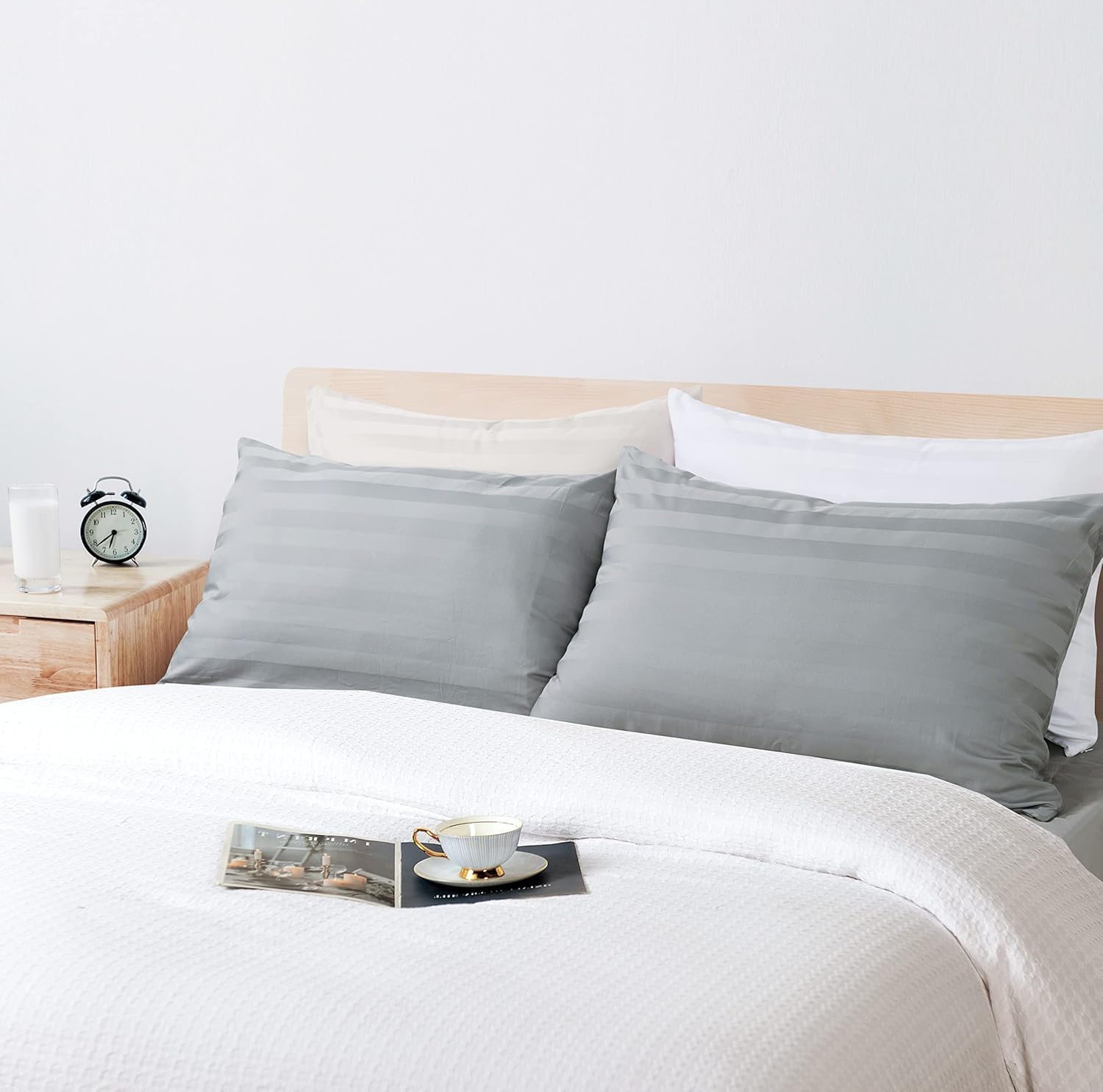 Grey stripe pillows styled on a bed with hotel-style bedding