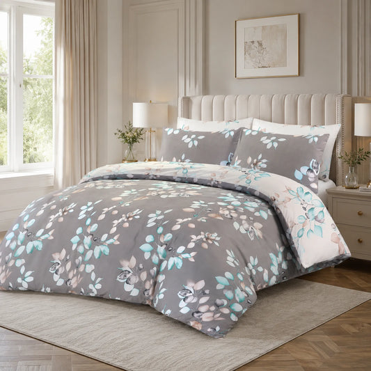 Grey duvet cover set with a teal, blush and cream leaf branch print, styled on a bed with a tufted headboard and two matching pillowcases