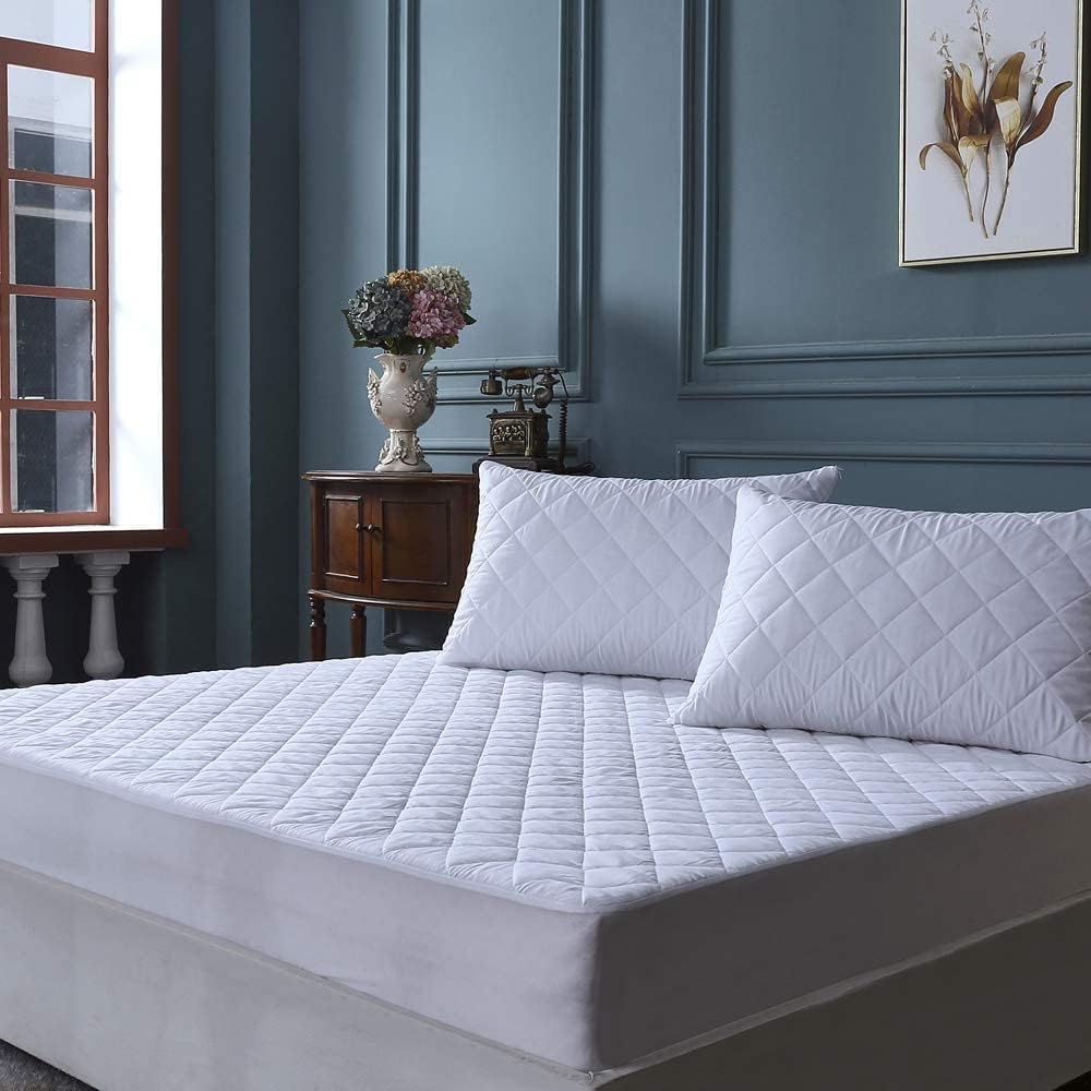 Quilted mattress protector styled on bed with matching pillows