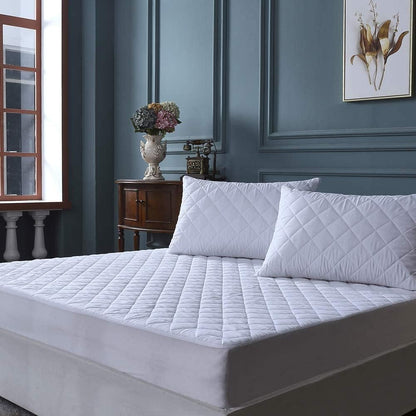 Quilted mattress protector styled on bed with matching pillows