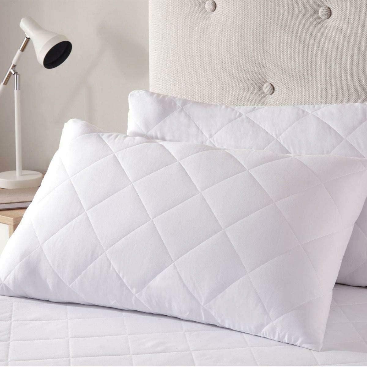 Quilted pillow protectors styled on a bed with white bedding